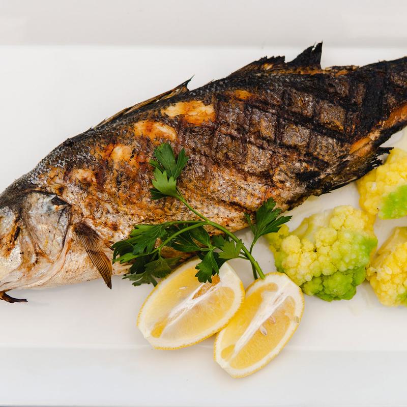 Grilled bass fish served with lemon wedges