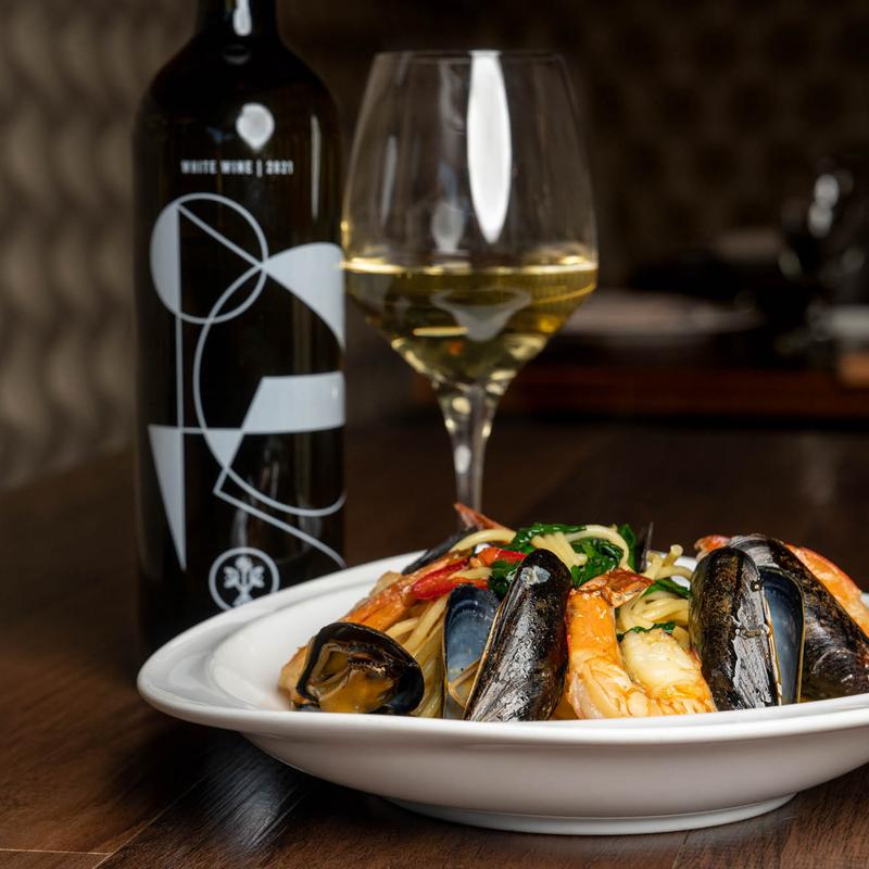 Mussels beside a glass and bottle of white wine