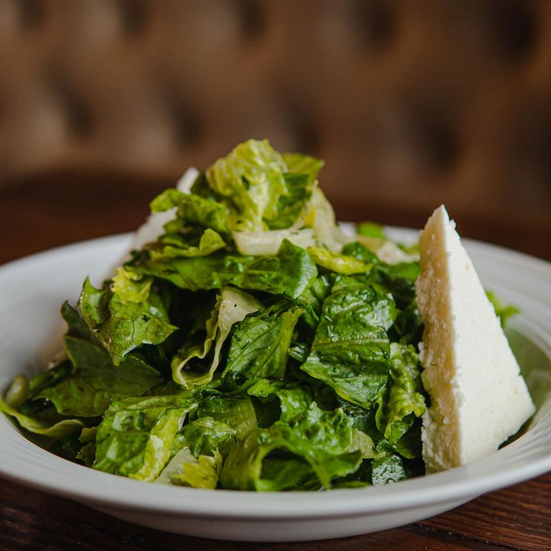 Green salad with shaved cheese on a white plate